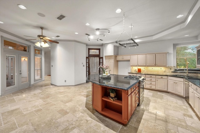 kitchen featuring sink, decorative backsplash, high end stainless steel range oven, a center island, and crown molding