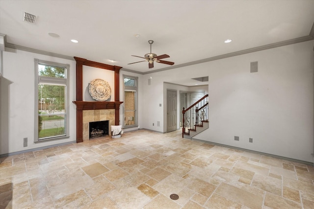 unfurnished living room with visible vents, a ceiling fan, stone tile flooring, crown molding, and a fireplace