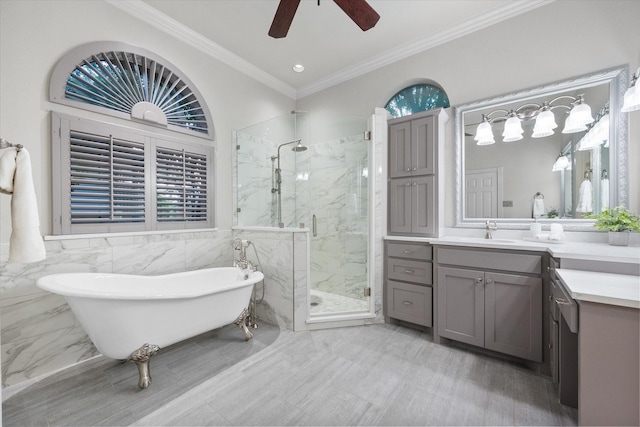 full bathroom featuring a marble finish shower, a freestanding bath, ceiling fan, vanity, and ornamental molding
