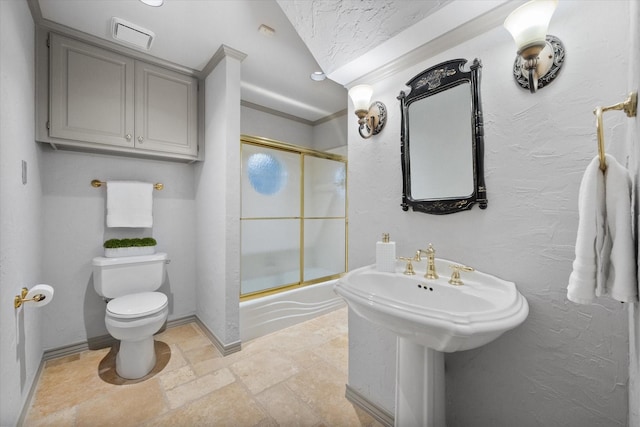 bathroom with combined bath / shower with glass door, stone tile flooring, a textured wall, and toilet