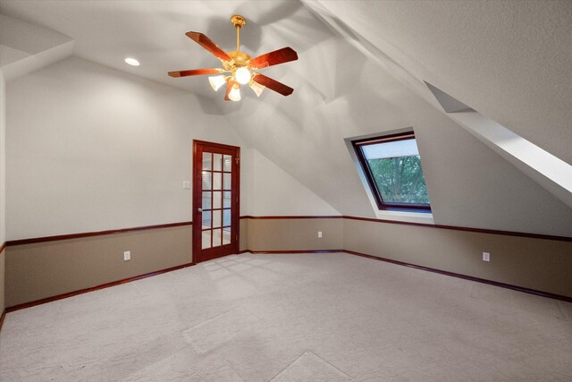 additional living space with lofted ceiling, light carpet, and ceiling fan