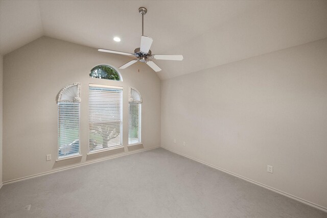 carpeted empty room featuring lofted ceiling, a ceiling fan, and baseboards