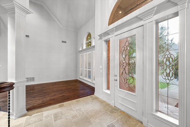 entrance foyer featuring crown molding, high vaulted ceiling, light hardwood / wood-style floors, and decorative columns