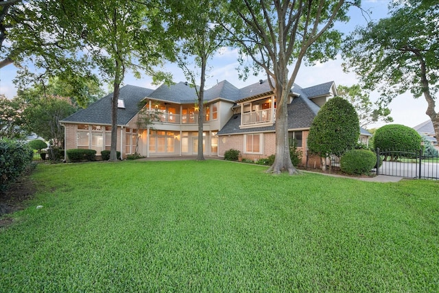 back of property with brick siding, a yard, and a balcony