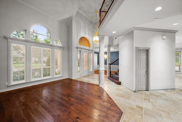 foyer featuring decorative columns, a towering ceiling, baseboards, stairway, and crown molding