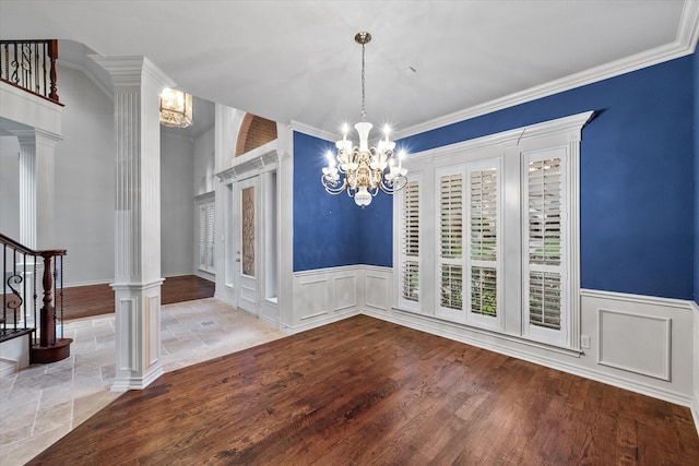 unfurnished dining area featuring decorative columns, hardwood / wood-style floors, and a notable chandelier