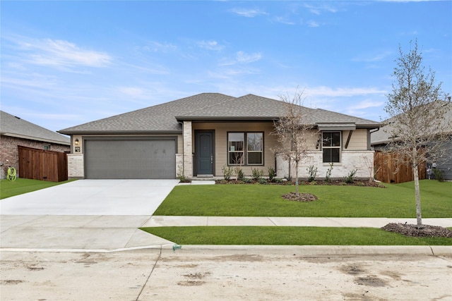 view of front of property with an attached garage, fence, concrete driveway, roof with shingles, and a front lawn