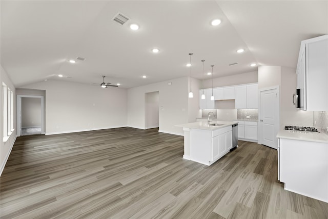 kitchen with open floor plan, appliances with stainless steel finishes, a sink, and lofted ceiling