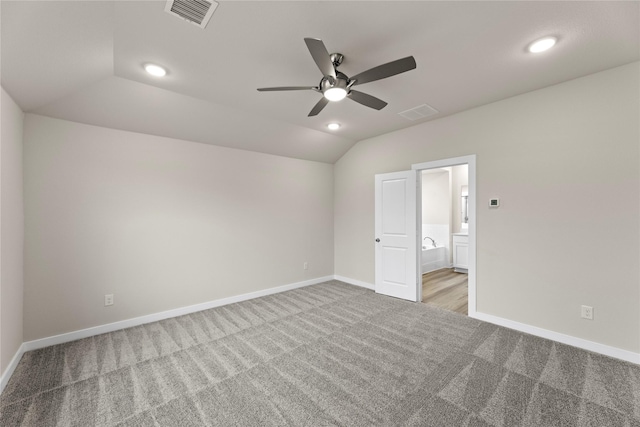 carpeted spare room with vaulted ceiling, ceiling fan, visible vents, and baseboards