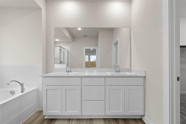 full bathroom featuring a stall shower, a garden tub, a sink, and double vanity