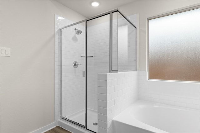 bathroom with a stall shower, baseboards, and a bath