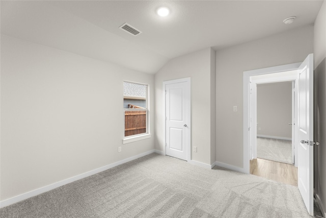 unfurnished bedroom featuring vaulted ceiling, carpet, visible vents, and baseboards