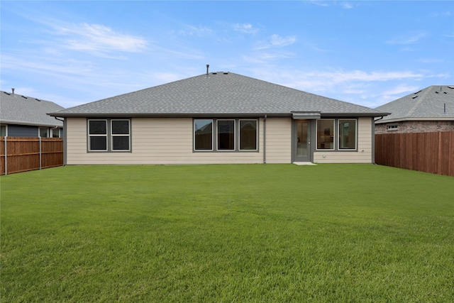 rear view of property featuring a fenced backyard, a lawn, and roof with shingles