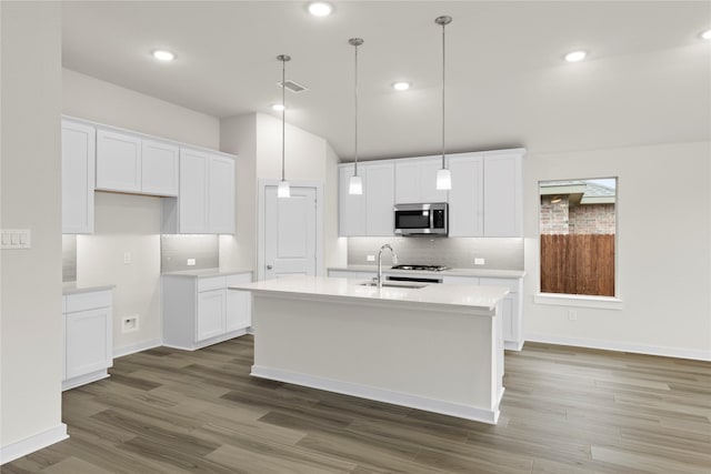 kitchen with white cabinets, stainless steel microwave, a sink, and an island with sink