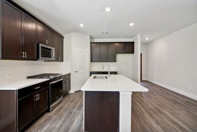 kitchen with wood finished floors, visible vents, a sink, appliances with stainless steel finishes, and backsplash