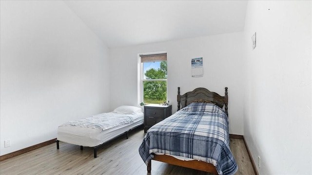 bedroom with vaulted ceiling and light hardwood / wood-style flooring