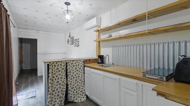 kitchen featuring pendant lighting, a wall mounted air conditioner, dark wood-type flooring, white cabinets, and sink