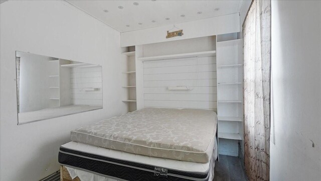 kitchen with sink, white cabinetry, a wall mounted AC, hanging light fixtures, and wooden walls