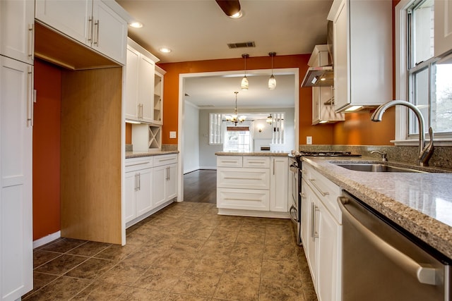 kitchen featuring sink, stainless steel dishwasher, pendant lighting, light stone countertops, and white cabinets