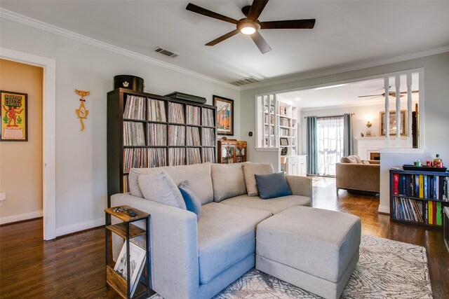 unfurnished living room featuring dark wood-type flooring, crown molding, built in desk, a brick fireplace, and ceiling fan