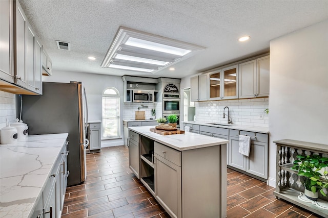 kitchen with gray cabinetry, sink, stainless steel appliances, and dark wood-type flooring