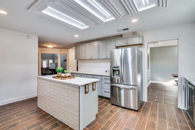 kitchen featuring gray cabinets, stainless steel fridge, a center island, and a textured ceiling