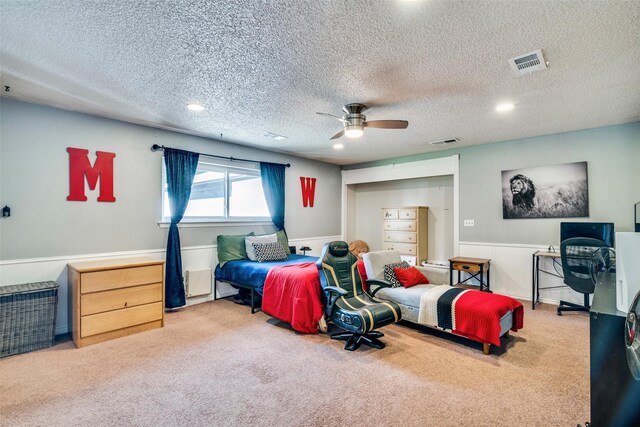 carpeted bedroom featuring ceiling fan and a textured ceiling