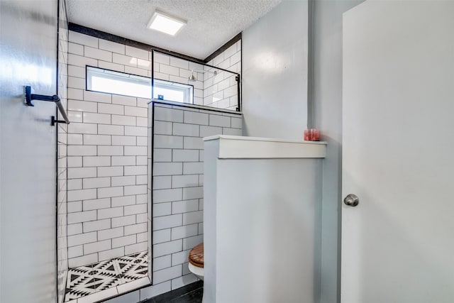 bathroom with tiled shower, a textured ceiling, and toilet