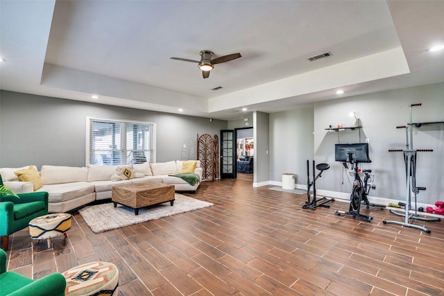 living room with a tray ceiling, ceiling fan, and hardwood / wood-style flooring