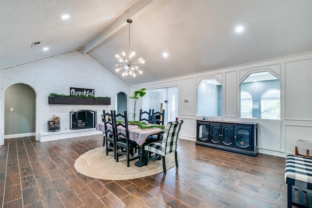 dining room featuring vaulted ceiling with beams, dark hardwood / wood-style floors, a fireplace, and a textured ceiling