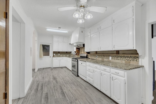 kitchen featuring white cabinets, custom exhaust hood, stainless steel gas range oven, and stone counters