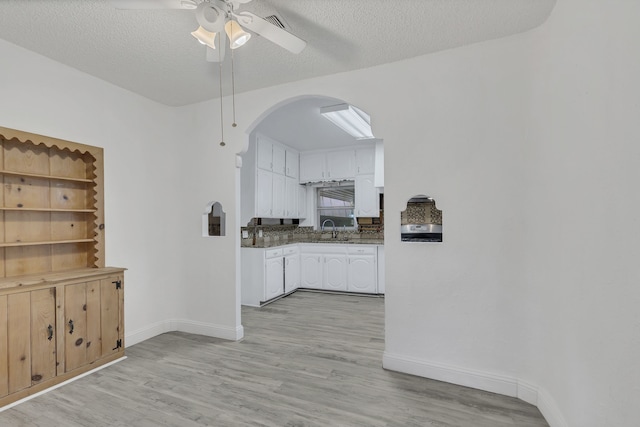 kitchen with a textured ceiling, ceiling fan, sink, light hardwood / wood-style flooring, and white cabinets