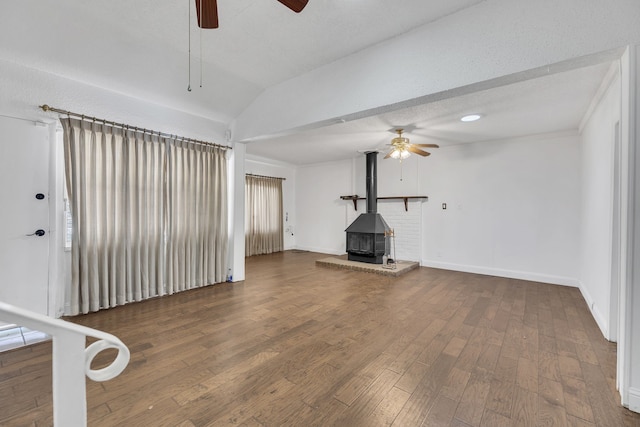 unfurnished living room with a textured ceiling, vaulted ceiling, ceiling fan, dark hardwood / wood-style floors, and a wood stove