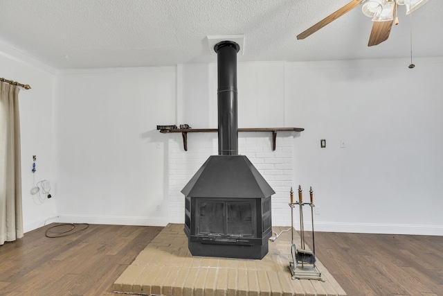 room details featuring hardwood / wood-style floors, ceiling fan, a wood stove, and a textured ceiling