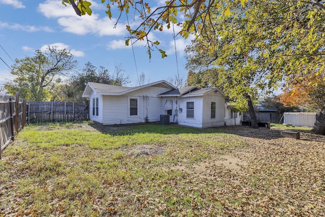 rear view of house with central AC and a yard