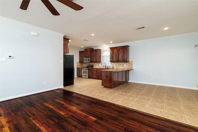 kitchen featuring ornamental molding, backsplash, appliances with stainless steel finishes, and light hardwood / wood-style flooring