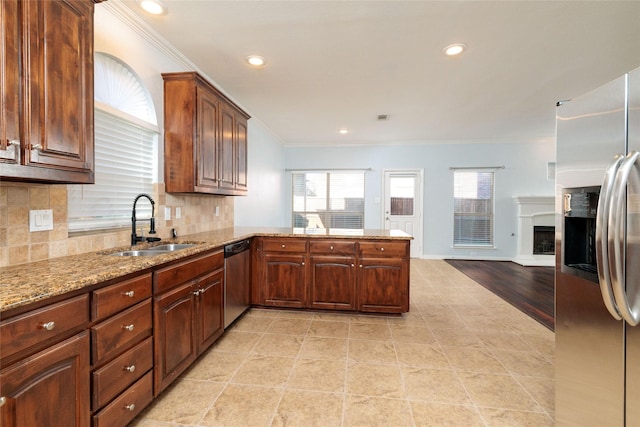 kitchen with kitchen peninsula, backsplash, stainless steel appliances, crown molding, and sink