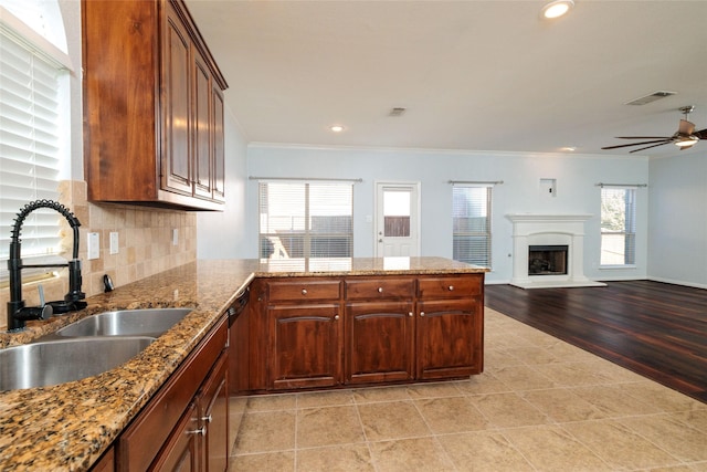 kitchen featuring light stone countertops, tasteful backsplash, crown molding, sink, and light hardwood / wood-style floors