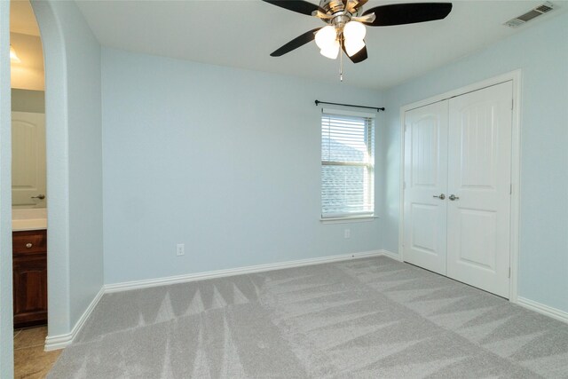 unfurnished bedroom featuring a closet, light colored carpet, and ceiling fan