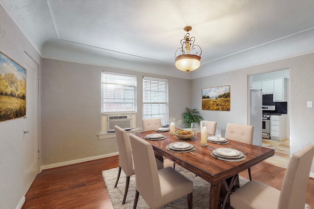 dining area with cooling unit, light wood-type flooring, and a textured ceiling