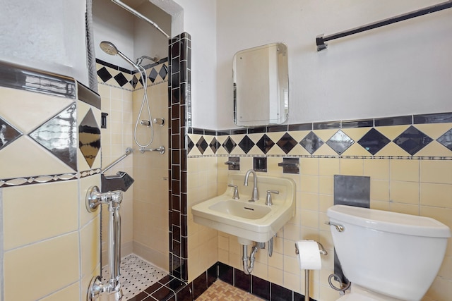 bathroom featuring a tile shower, sink, tile walls, and toilet