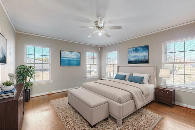 bedroom with multiple windows, light hardwood / wood-style flooring, ceiling fan, and ornamental molding