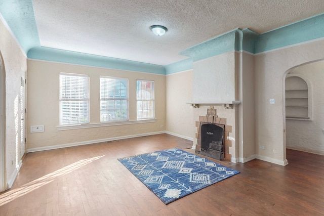 living room featuring a stone fireplace, lofted ceiling, hardwood / wood-style floors, and a textured ceiling