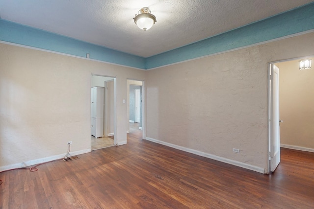 unfurnished room featuring dark wood-type flooring and a textured ceiling