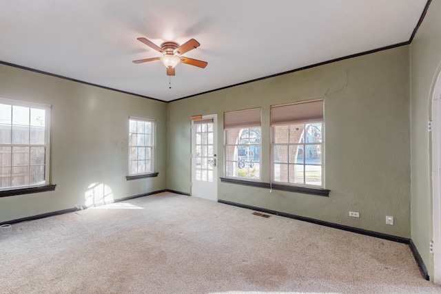 carpeted empty room with ceiling fan, plenty of natural light, and crown molding