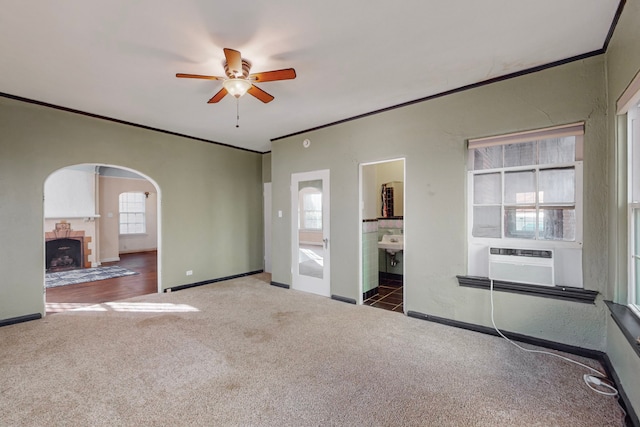 interior space featuring a tile fireplace, cooling unit, ornamental molding, and ceiling fan