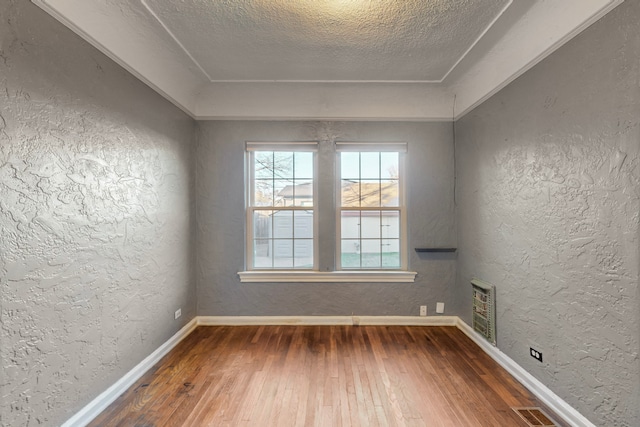 empty room with wood-type flooring and a textured ceiling