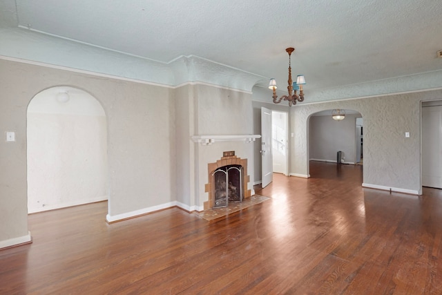 unfurnished living room with ornamental molding, dark wood-type flooring, a textured ceiling, and a notable chandelier