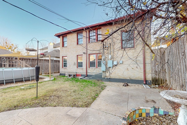 rear view of property featuring a fenced in pool, a yard, and a patio