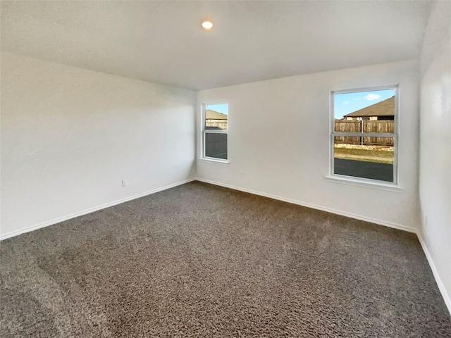 spare room with plenty of natural light and dark carpet